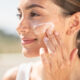 mujer poniendose protector solar en el exterior primer plano