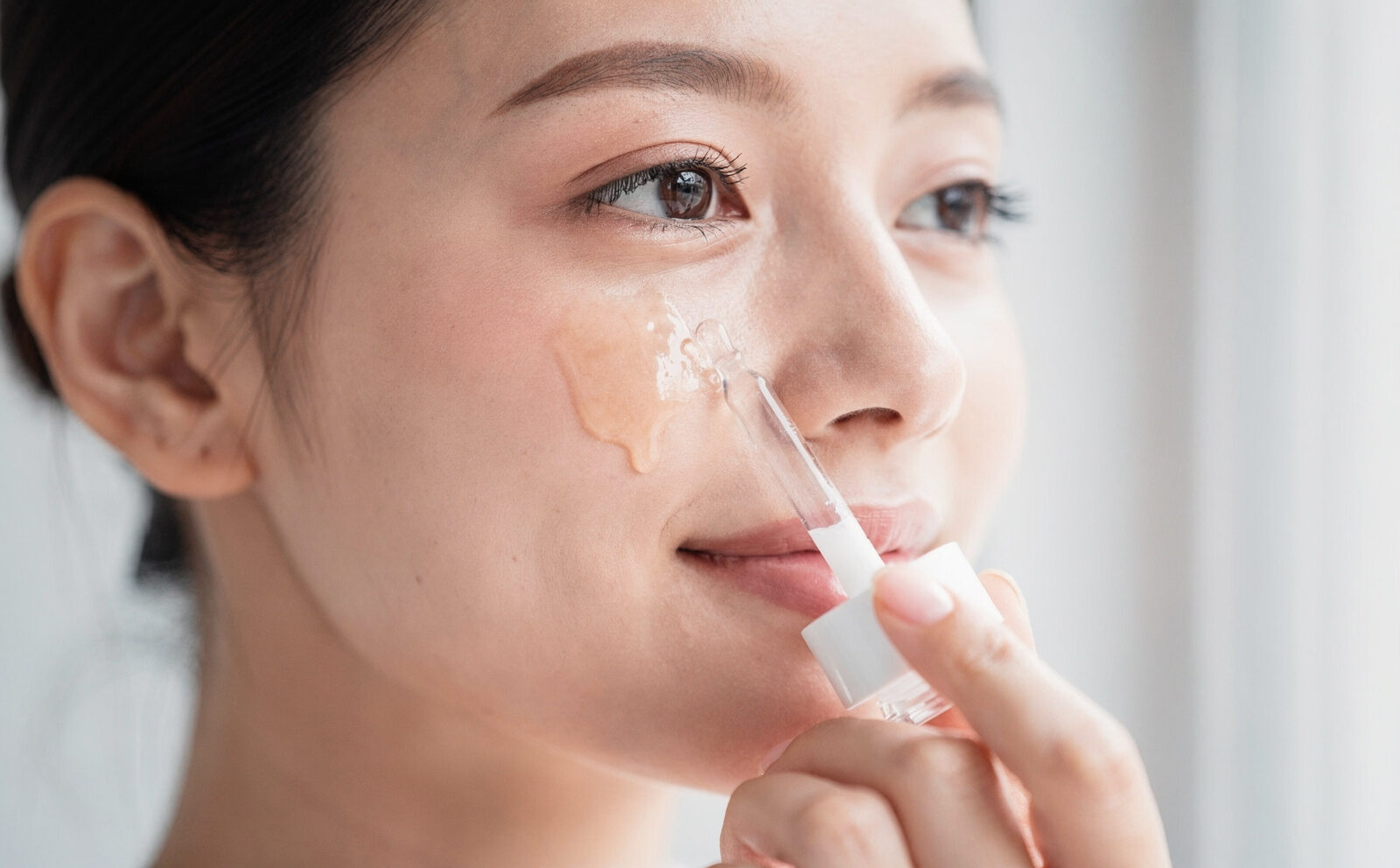 Aplicación del sérum sobre el rostro, gesto de skincare en curso; sin celebridades; sin mostrar resultado final de la piel.