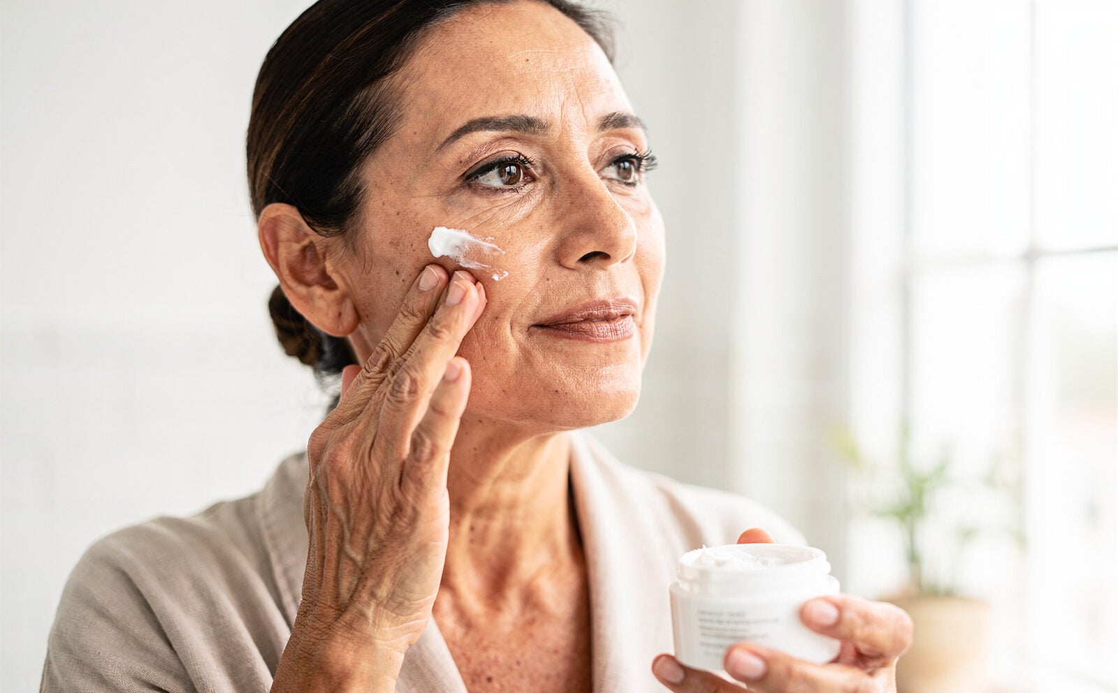 mujer poniendose crema facial antiarrugas