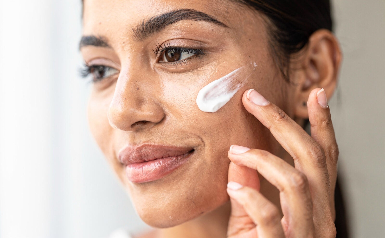 mujer se pone crema facial en la cara primer plano