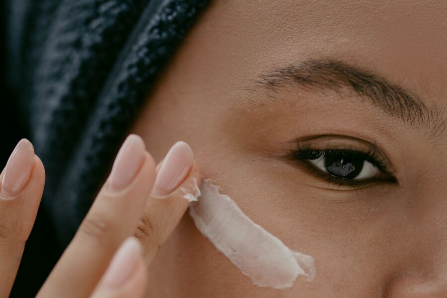 Primer plano extremo de una mujer que se aplica crema en la mejilla para un cuidado saludable de la piel.