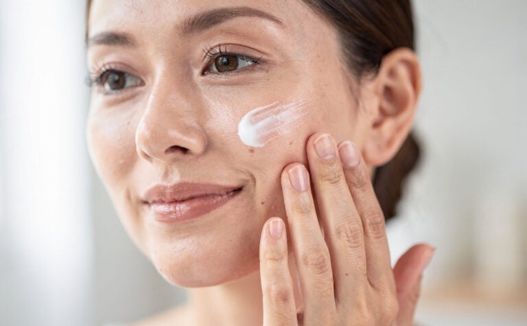 mujer se pone crema en la cara