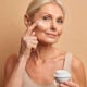 Hermosa mujer de mediana edad aplica crema antienvejecimiento en la cara se somete a tratamientos de belleza se preocupa por la piel