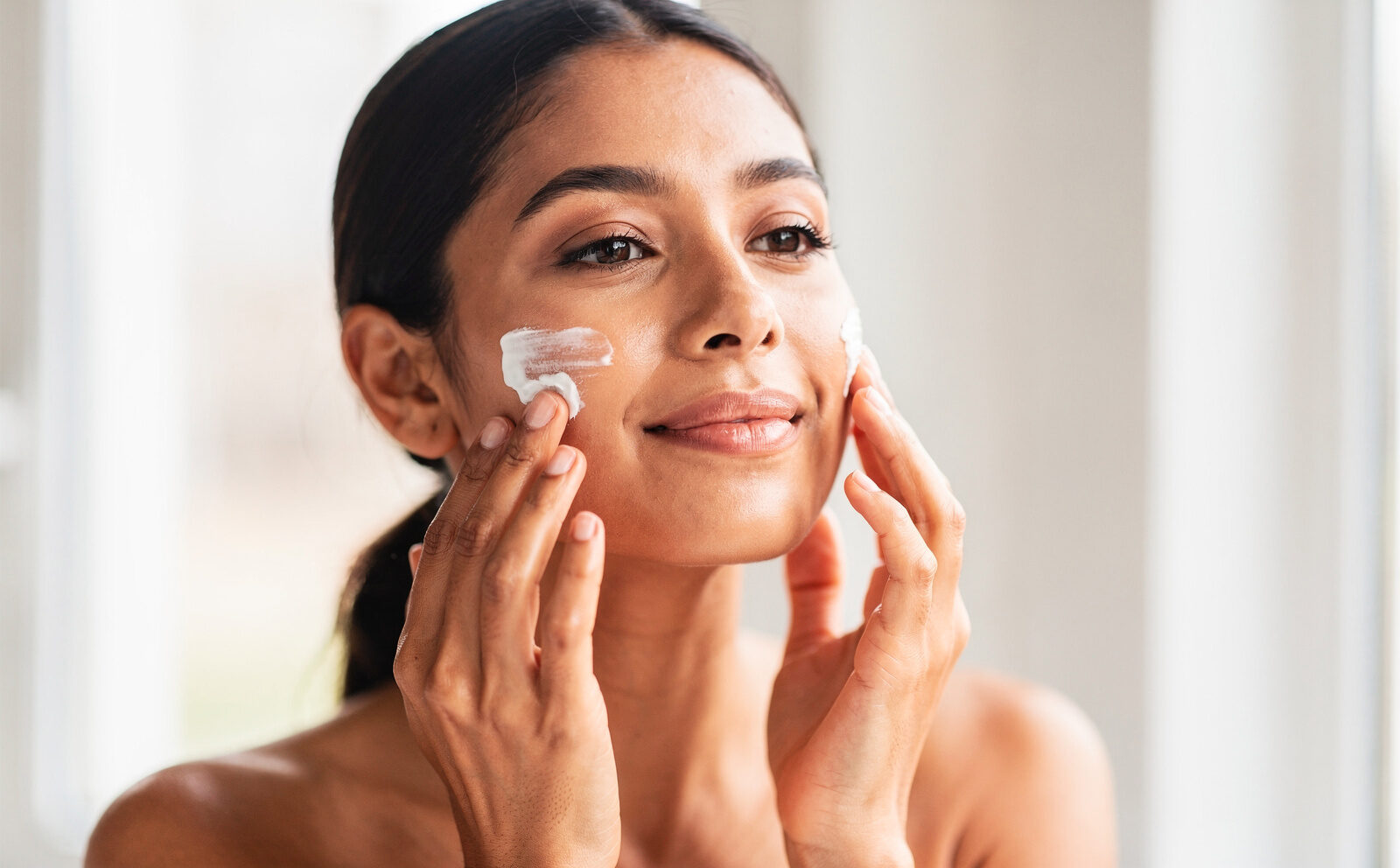 mujer se pone crema en el rostro