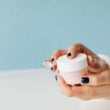 Imagen de cerca de las manos sosteniendo un frasco de crema para el cuidado de la piel, centrándose en productos de belleza y cuidado personal.