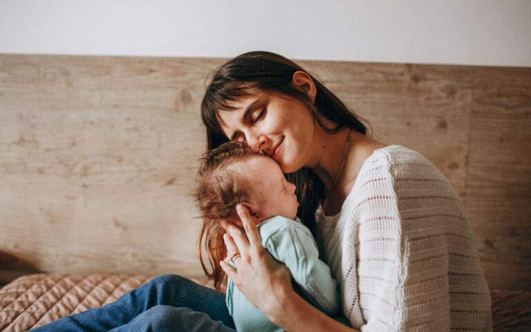 Un momento de amor entre una madre y su bebé, compartiendo un tierno abrazo en el interior.