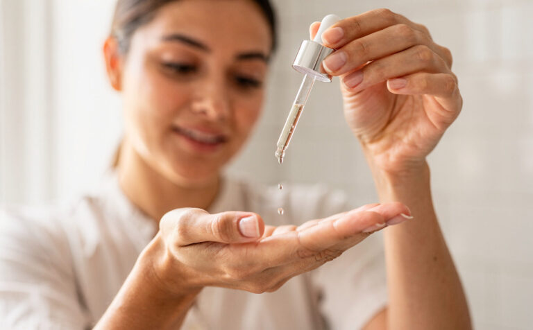 Mujer poniendose en la mano gotas de serum