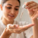 Mujer poniendose en la mano gotas de serum