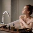 Una serena escena de baño con una mujer disfrutando de la relajación con incienso y una taza de té caliente.