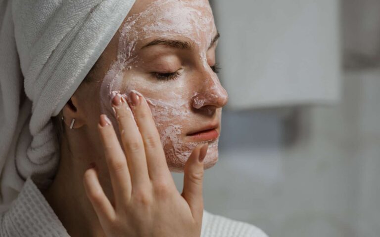 Una mujer aplica una mascarilla de arcilla como parte de su régimen de belleza de autocuidado en interiores.