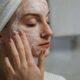 Una mujer aplica una mascarilla de arcilla como parte de su régimen de belleza de autocuidado en interiores.