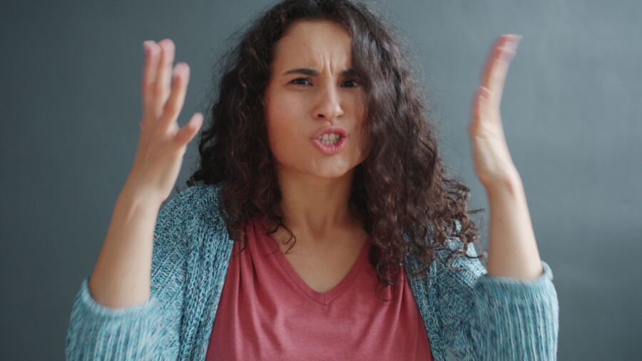 Mujer joven expresando emociones con gestos animados en interiores.