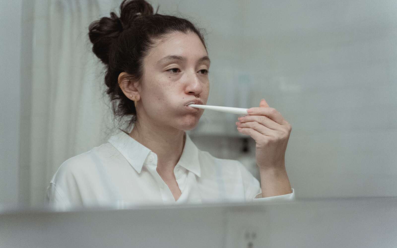 Vista lateral de una mujer cepillándose los dientes, centrándose en el cuidado dental y la higiene.