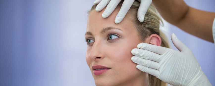 Doctor examinando pacientes femeninos cara de tratamiento cosmético