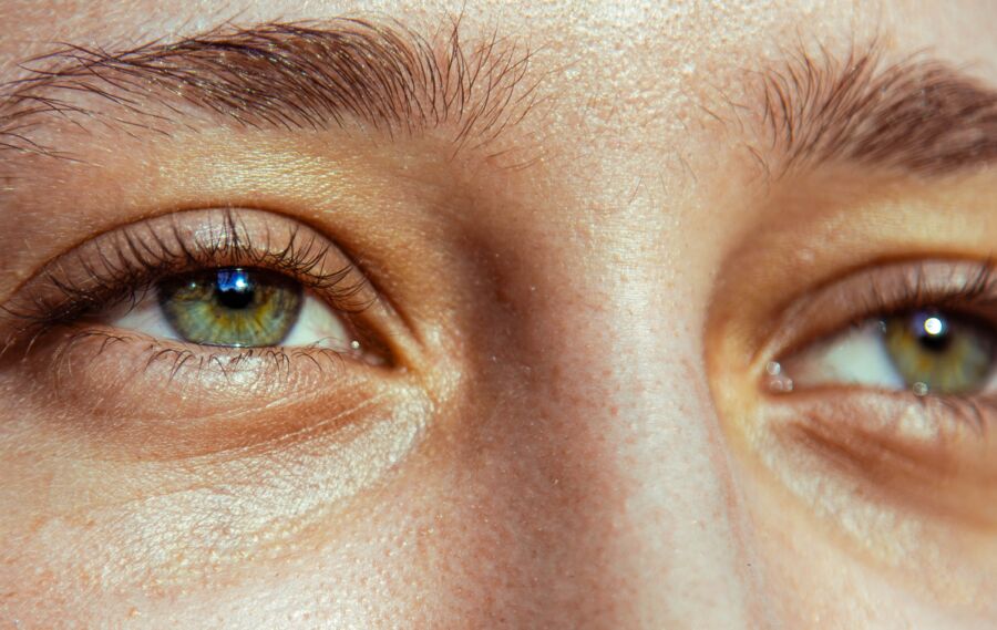 Un primer plano de ojos verdes capturados bajo la luz natural del sol, destacando detalles.
