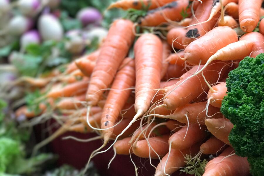 Primer plano de zanahorias orgánicas frescas apiladas en un mercado de agricultores con verduras.
