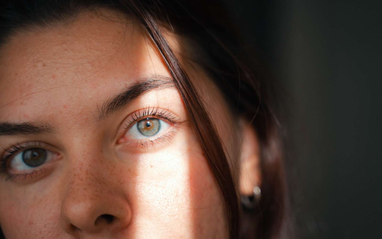 Primer plano íntimo de la cara de una mujer con luz natural suave, enfatizando las características.