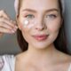 Mujer sonriente aplicando crema facial para la rutina de cuidado de la piel