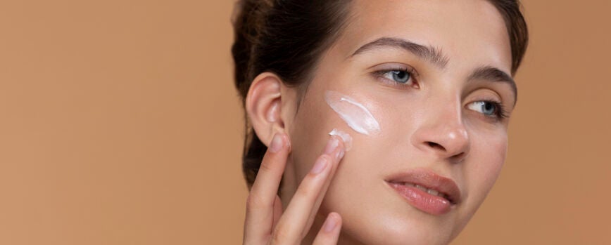 Mujer de vista lateral usando crema para la cara