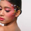 Mujer con maquillaje rosa y adornos en su rostro aislado en blanco