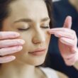 Primer plano de una mujer con los ojos cerrados recibiendo atención facial en una clínica de belleza en el interior.