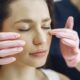 Primer plano de una mujer con los ojos cerrados recibiendo atención facial en una clínica de belleza en el interior.