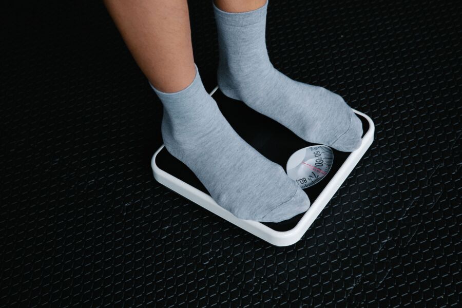Primer plano de los pies en calcetines de pie sobre una báscula, centrándose en la medición del peso.