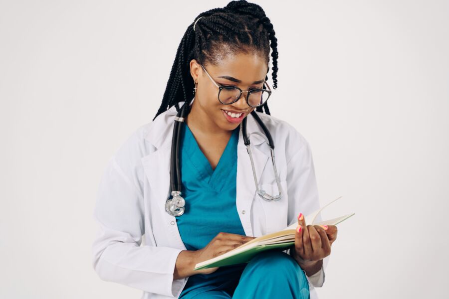 Médica sonriente con estetoscopio leyendo documentos médicos.