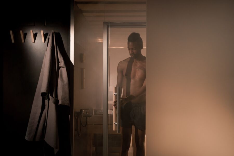 Un hombre sin camisa entra en una ducha llena de vapor, creando un ambiente íntimo y relajante.