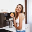 Riendo a joven sosteniendo naranja en la cocina