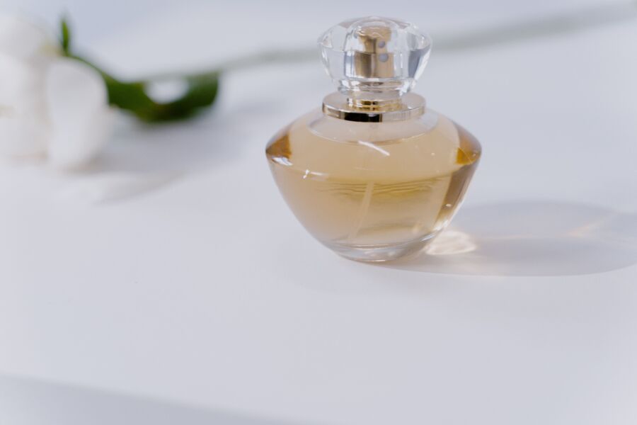 Un frasco de perfume transparente con fragancia sobre una mesa blanca minimalista, rebosante de elegancia.