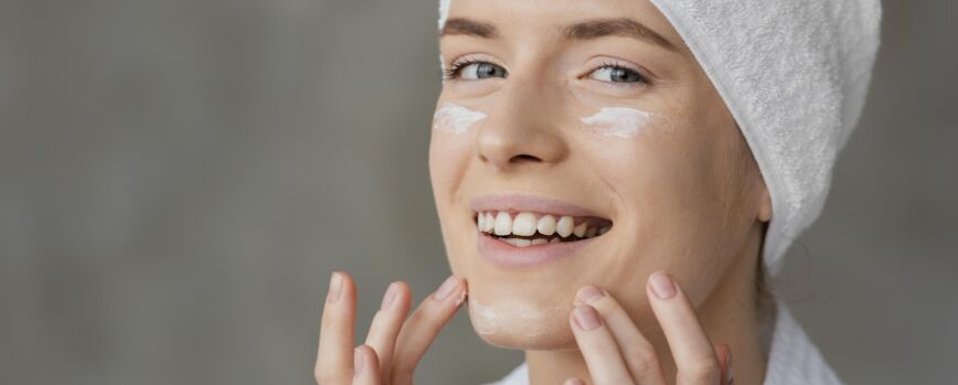 Bella mujer con una crema para el cuidado de la piel