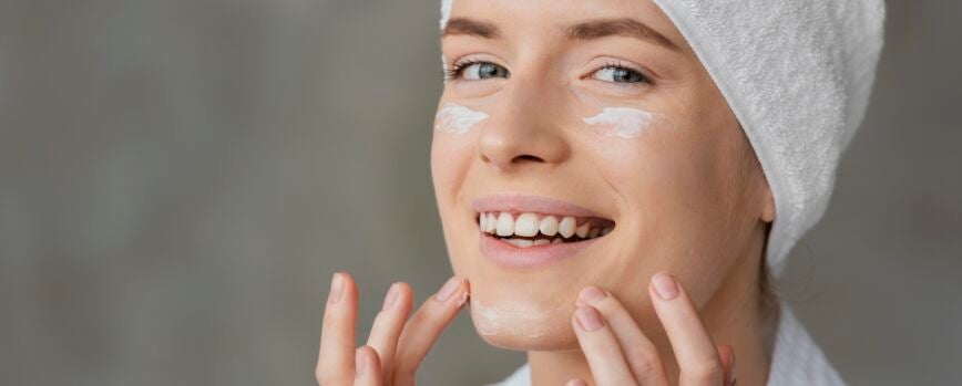 Bella mujer con una crema para el cuidado de la piel