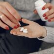 Un primer plano de una mujer entregando medicamentos a la mano de un hombre, simbolizando el cuidado y el apoyo.
