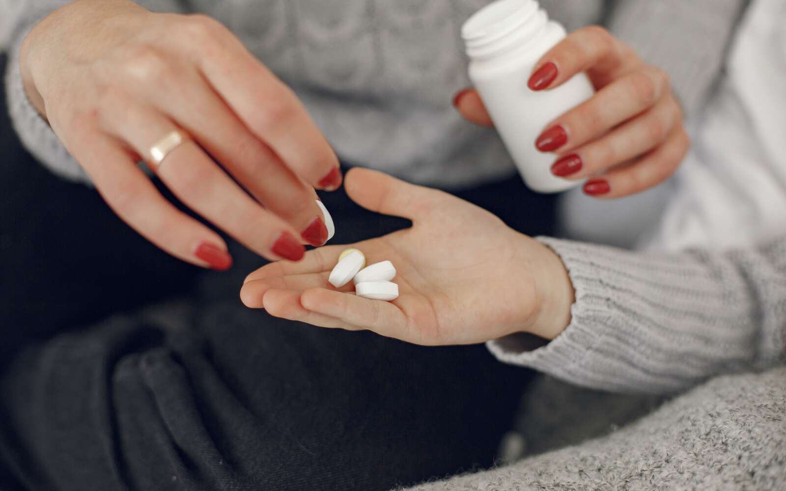 Un primer plano de una mujer entregando medicamentos a la mano de un hombre, simbolizando el cuidado y el apoyo.
