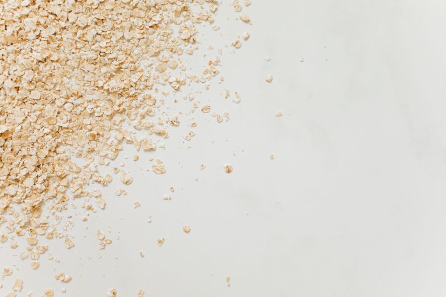 Primer plano de avena esparcida sobre un fondo blanco limpio, perfecto para temas relacionados con la alimentación.