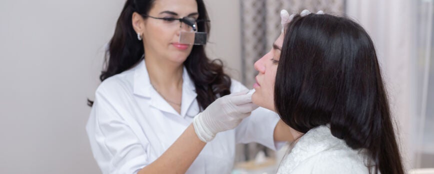 Un cliente en una cita con un esteticista, consulta, modelado de la cara, preparación para los próximos procedimientos, examen visual de las áreas problemáticas.