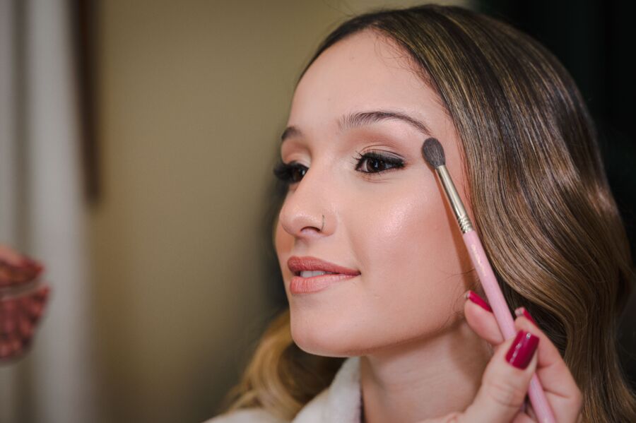 Primer plano de una joven maquillándose con pincel, mostrando belleza y elegancia.