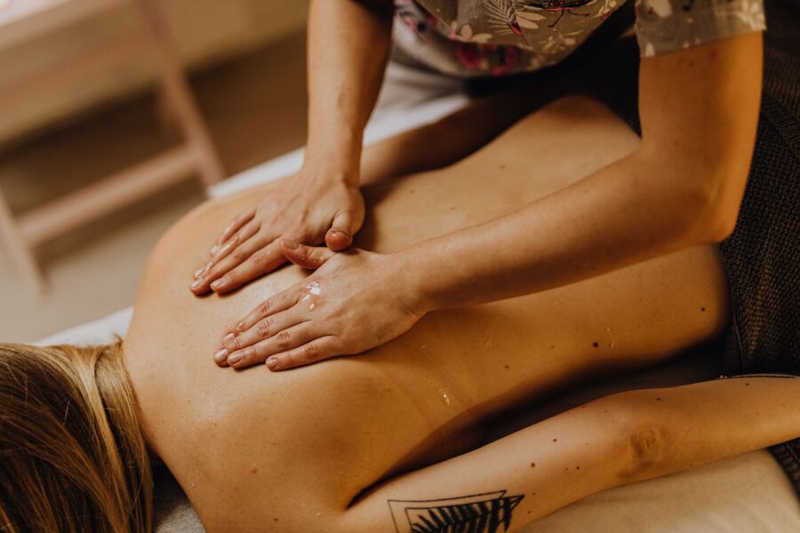 Primer plano de un relajante masaje de espalda en un spa con las manos aplicando aceite de masaje.