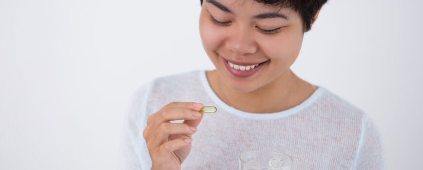 Sonriente joven bastante asiática mujer tomando píldora