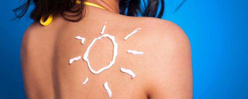 Loción bronceadora en el brazo de la mujer en forma de sol