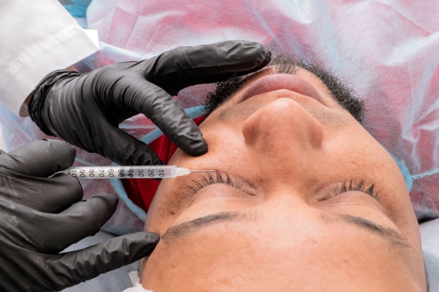 Hombre recibiendo tratamiento facial con jeringa en centro médico.