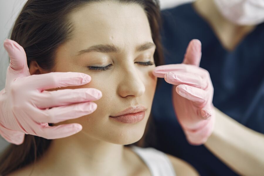 Primer plano de una mujer con los ojos cerrados recibiendo atención facial en una clínica de belleza en el interior.
