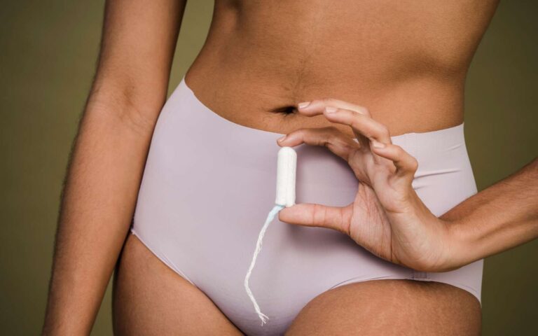 Recortar mujer anónima en ropa interior demostrando tampón suave sobre fondo de olivo de estudio