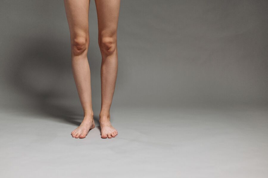 Foto de estudio de la parte inferior de las piernas y los pies de una persona sobre un fondo gris.