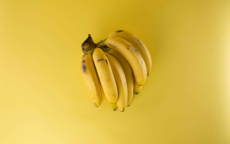 Un vibrante racimo de plátanos maduros sobre un fondo amarillo a juego, que evoca frescura.