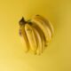Un vibrante racimo de plátanos maduros sobre un fondo amarillo a juego, que evoca frescura.