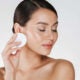 Cuidado de la piel y tratamiento saludable de la mujer que quita el maquillaje de la cara con un algodón, aislado en blanco