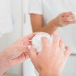 Primer plano de la mano de la mujer que aplica la crema hidratante