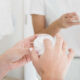 Primer plano de la mano de la mujer que aplica la crema hidratante